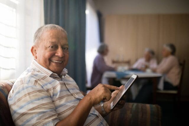 Un senior con un tablet sorridente per i vantaggi di accedi con Spid.