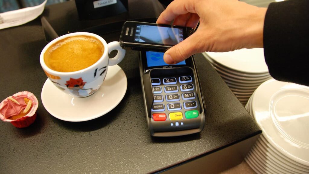 Cellulare su pos per pagare un caffè al bar con Android Pay.