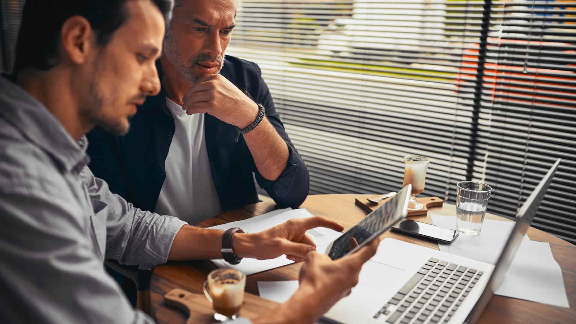 Due imprenditori al tavolo con un portatile che si informano sulla direttiva NIS 2.