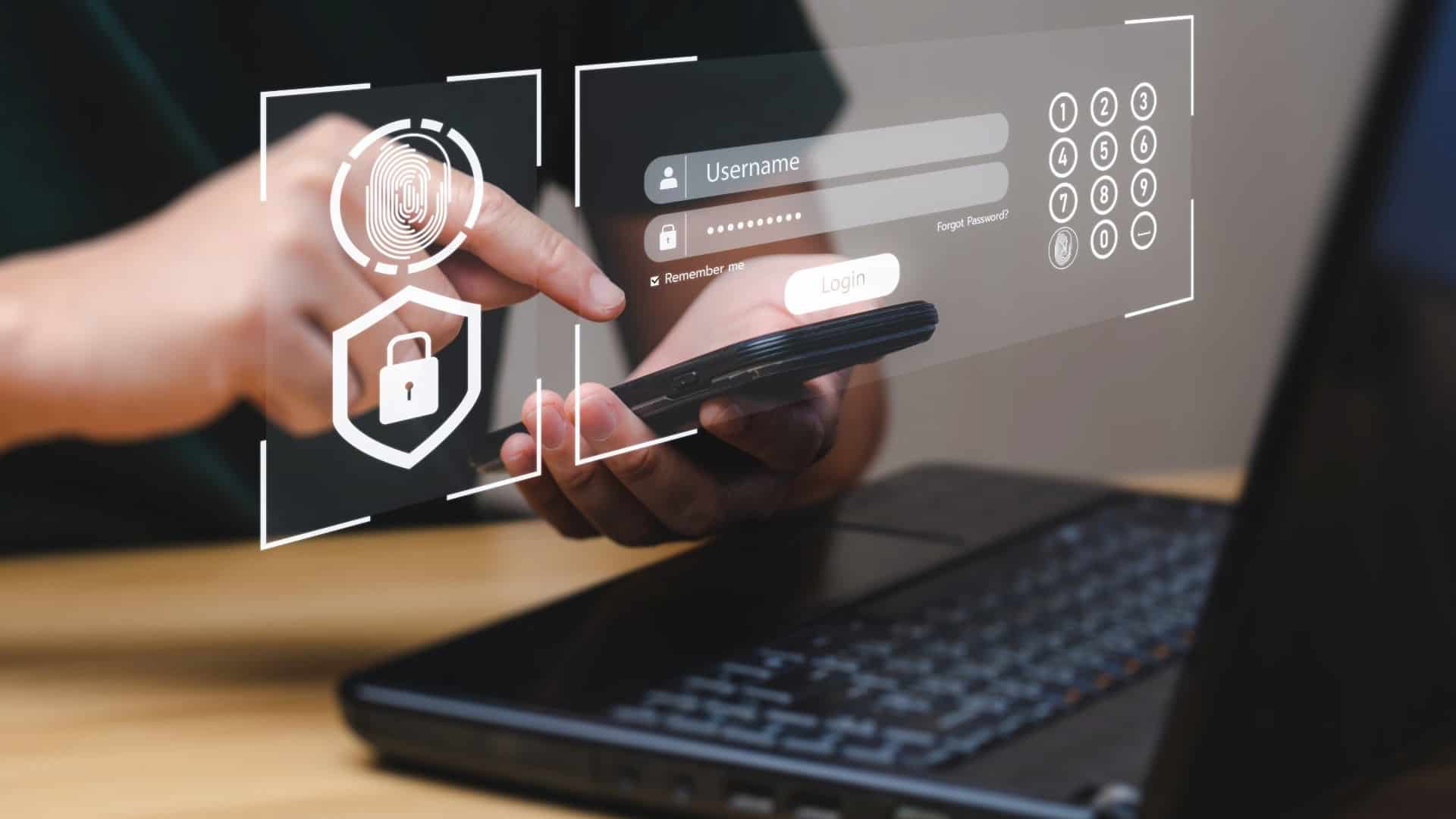 Delle mani che tengono uno smartphone davanti a un portatile.