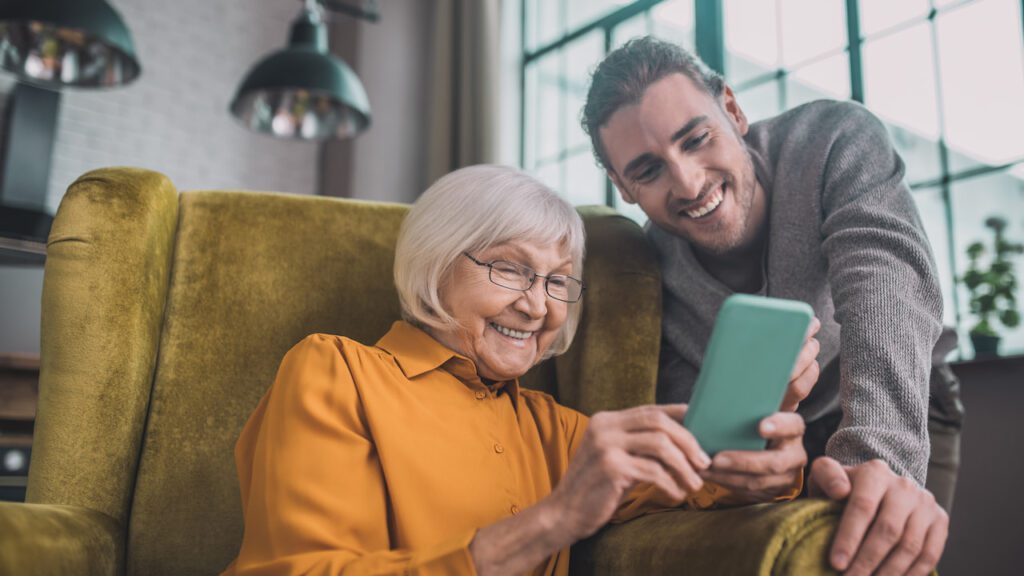 Con il servizio civile digitale un giovane facilitatore digitale aiuta una donna anziana a usare lo smartphone.