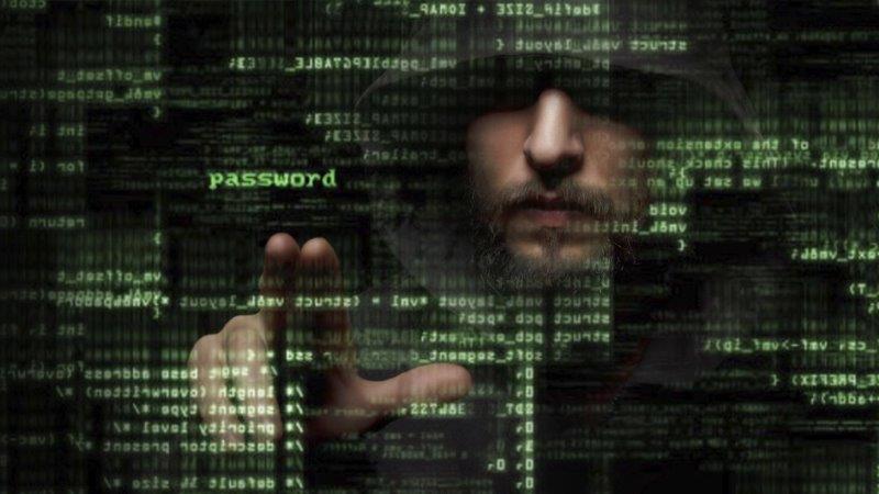 Un hacker dietro a uno schermo con codici compie attacchi informatici con uso illecito dei certificati digitali.